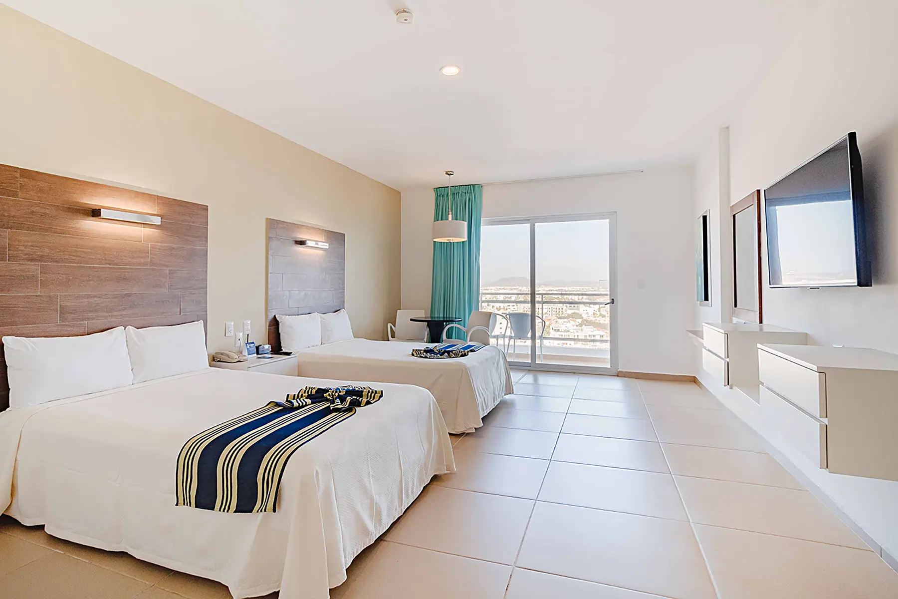 Habitación dos camas matrimoniales, vista a la ciudad con balcón, tv , espejo de vanidad, mueble flotante con cajones, hotel pacifc palace Mazatlán